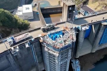熊本県の緑川第一発電所をドローンで撮影した5枚の写真。山あいにある発電所と貯水池の全景、青い水門、取水口設備を写している。取水口スクリーンの更新現場では、コンクリート構造物の上部と側面に足場やゴンドラが組まれ、トビノスと3Sシステムを組み合わせた作業設備が設置されている。